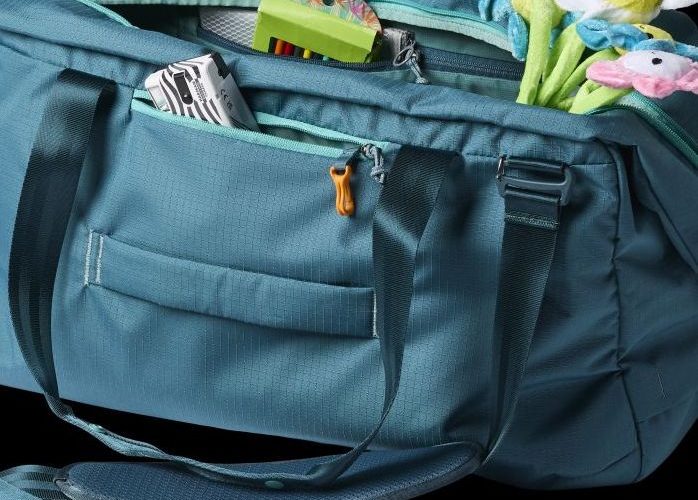 Cotopaxi Viaje 45L in blue with an assortment of things flowing out of its pockets